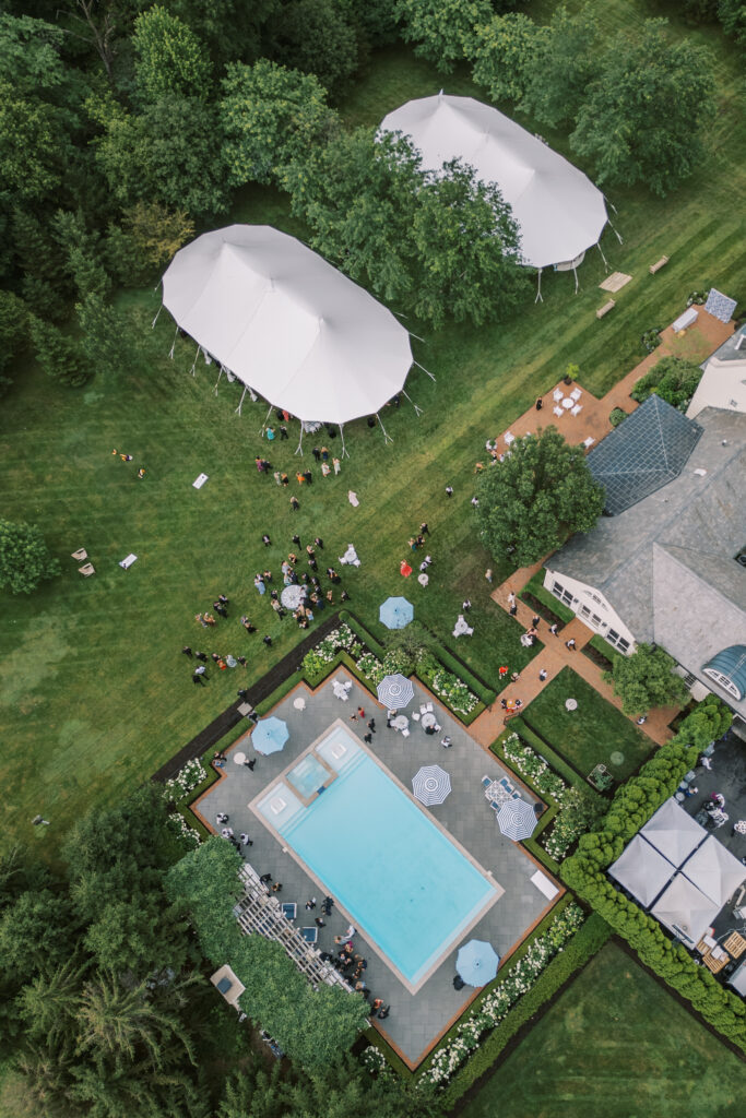Aerial and scenic views of a luxury tented estate wedding in Ohio, featuring two sailcloth tents, poolside cocktail hour spaces, and detailed outdoor setups planned by an expert Ohio wedding planner.