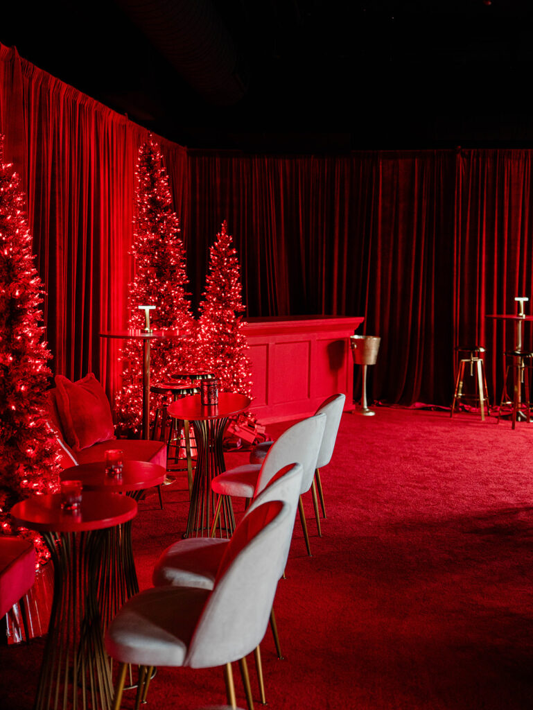 Red velvet-draped holiday pop-up bar table with brass lamp and cocktail designed by Columbus event designers Aisle & Co. at The Junto Hotel.
