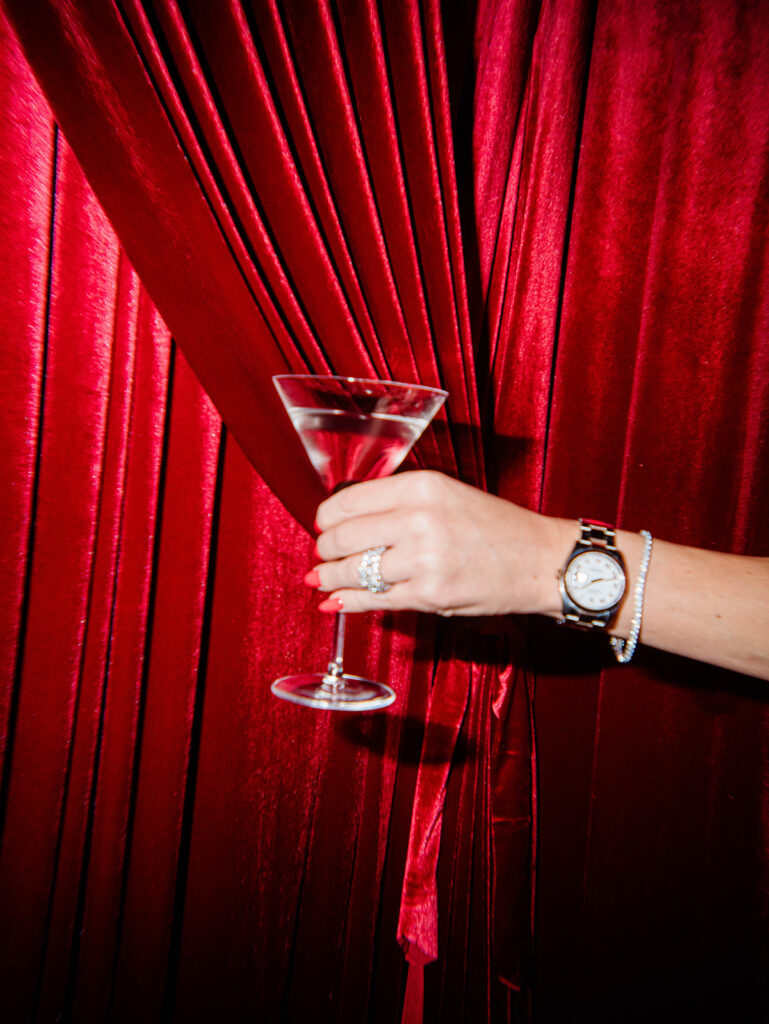 Festive moment with guest tossing a wrapped gift beside a red tinsel Christmas tree inside the Santa Baby holiday pop-up designed by Aisle & Co. in Columbus.
