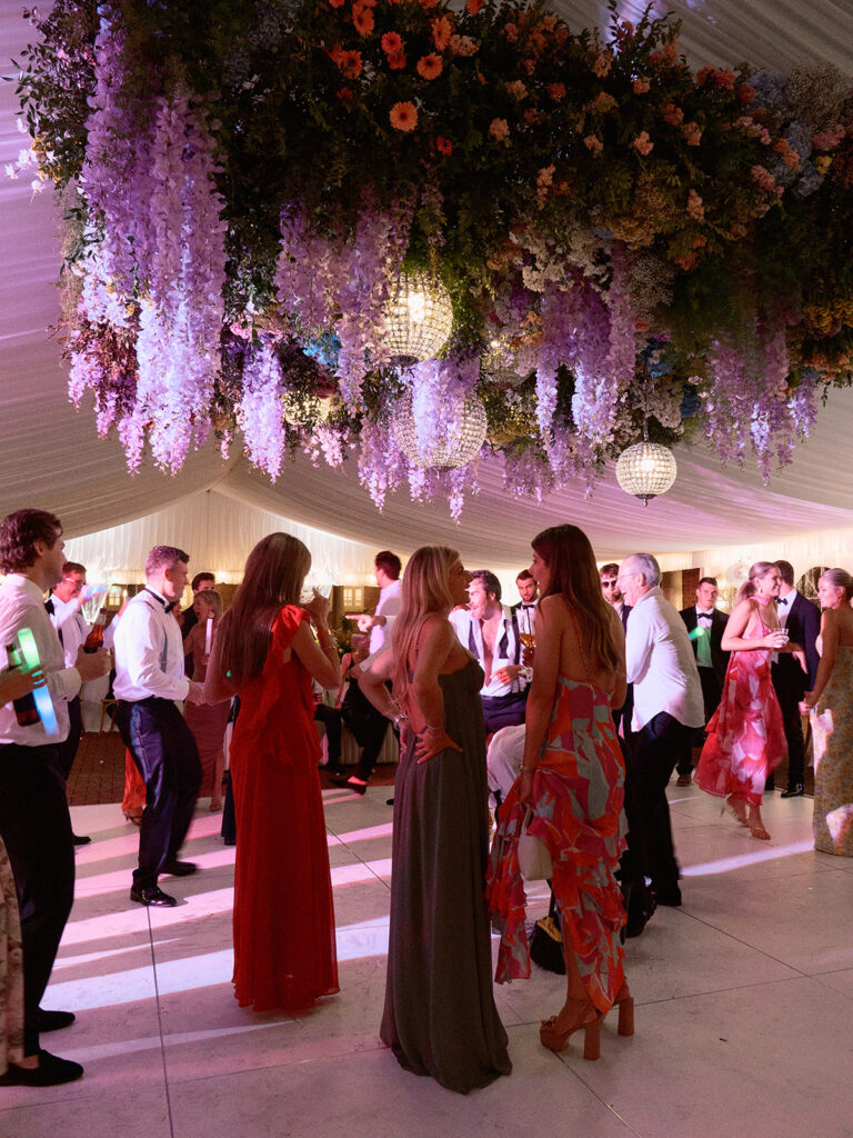 Tent reception with hanging floral ceiling and crystal chandeliers.
