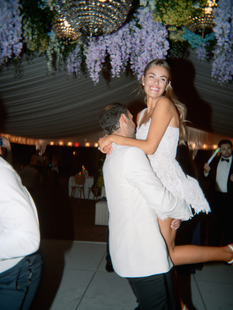 Tent reception with hanging floral ceiling and crystal chandeliers.