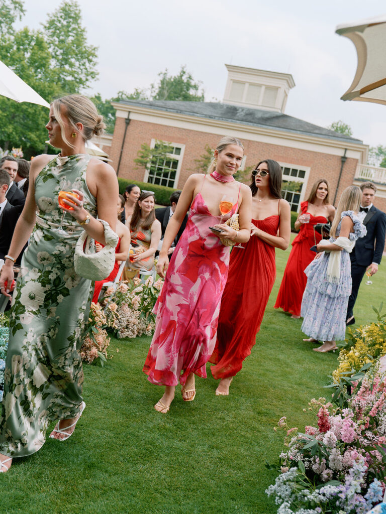 Guests holding Aperol Spritzes outside under white umbrellas.